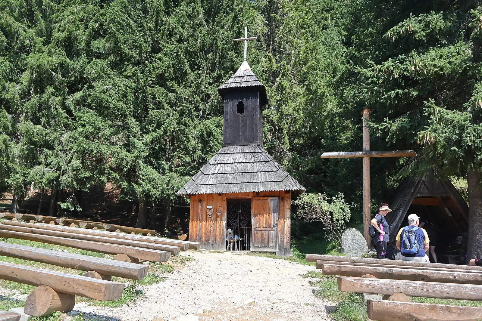 Mała drewniana kaplica św. Jana Chrzciciela na Polanie Chochołowskiej wśród smreków, przed nią ławki